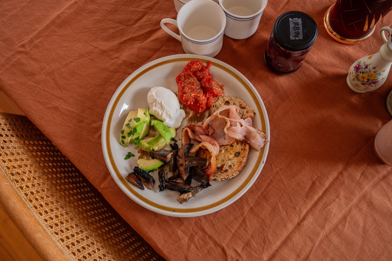 plate of breakfast with avocado, egg, tomato, toast, bacon, mushrooms