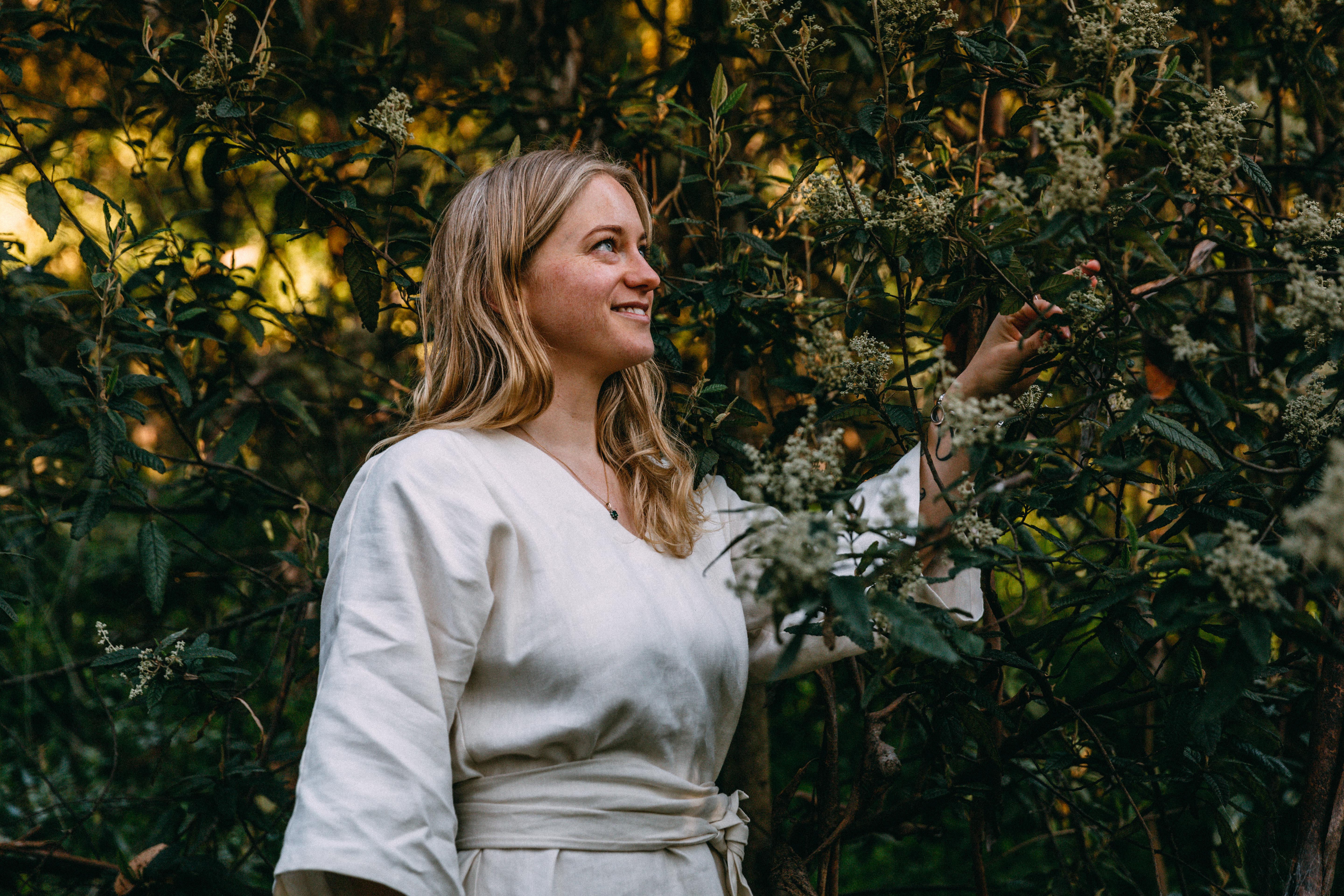 Beccy Bradshaw in a white dress, amongst some native flowers and foliage