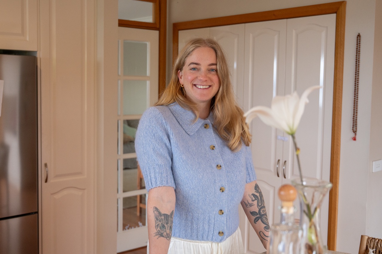 Beccy standing at her kitchen bench with a blue top on