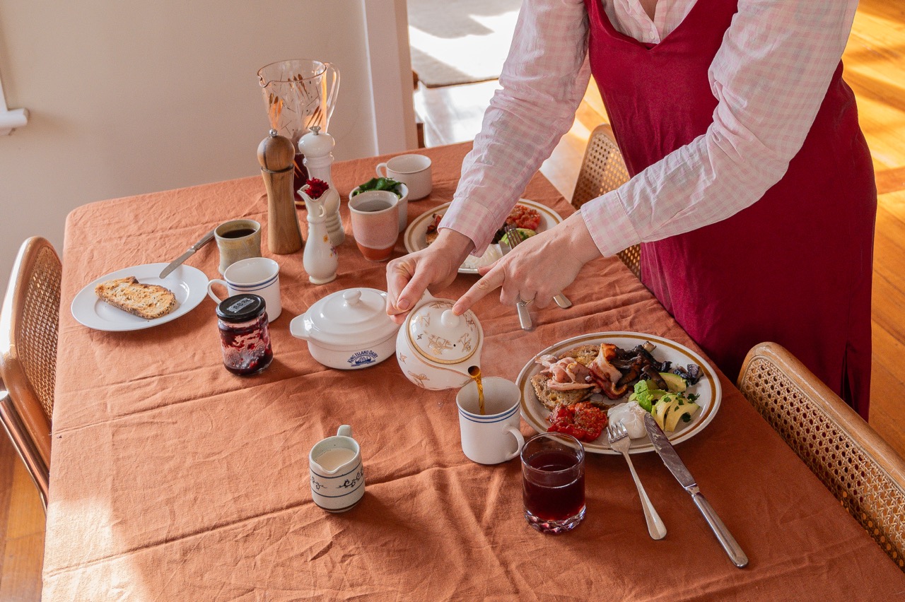 breakfast table of tea, plates of food, jam, juice
